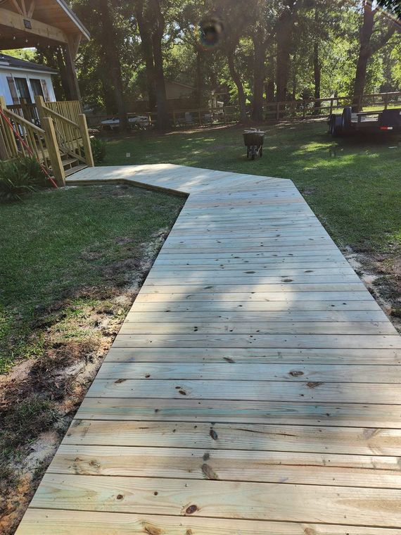 Long wooden boardwalk through a yard